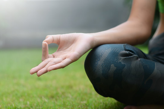 Close up at the hands of the woman is sitting yoga in the park