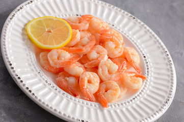 Cooked shrimps on the white plate with lemon.