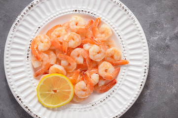 Cooked shrimps on the white plate with lemon.