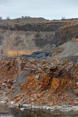 The wall of the sandstone quarry with dry trees without leaves