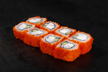 Sushi, rolls, uramaki, california, with tobiko caviar, avocado, cucumber, cheese, crab meat, raw seafood, soy sauce, marinated ginger and wasabi black isolated background Side view For the menu