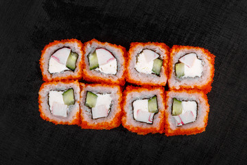 Sushi, rolls, uramaki, california, with tobiko caviar, avocado, cucumber, cheese, crab meat, raw seafood, soy sauce, marinated ginger and wasabi, black isolated background view from above For the menu