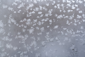 Winter icy pattern of frozen snowflakes on window pane. 