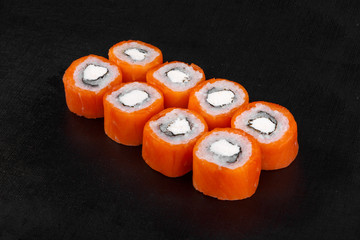 Sushi, rolls, uramaki, philadelphia, with salmon, crab meat, cheese, raw seafood, soy sauce, marinated ginger and wasabi, black isolated background Side view For the menu restaurant