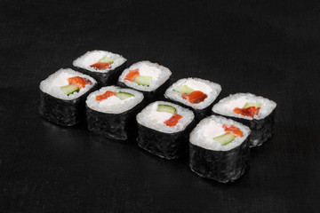 Sushi, rolls, hosomaki, with salmon, avocado, cucumber and Philadelphia cheese, raw seafood, soy sauce, marinated ginger and wasabi, black isolated background Side view For the menu, restaurant