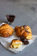 Tasty croissants with chocolate on grey concrete background.