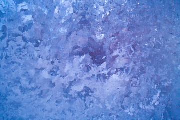 Illuminated with purple frosty blue icy pattern on window pane. 