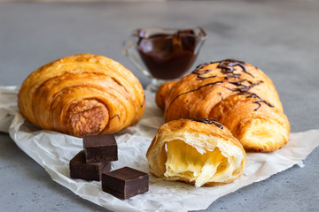 Tasty croissants with chocolate on grey concrete background.