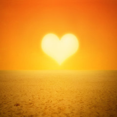 Fototapeta premium Zachód słońca w kształcie serca w krajobraz pustyni lub plaży ze śladami