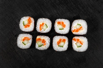 Sushi, rolls, hosomaki, with salmon, avocado, cucumber and Philadelphia cheese, raw seafood, soy sauce, marinated ginger and wasabi, black isolated background view from above For the menu