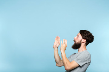 man looking sideways and is intimidated or scared by smth on the left. free space for advertisement. portrait of a bearded guy on blue background.