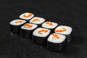 Sushi, rolls, hosomaki, with salmon, avocado, cucumber and Philadelphia cheese, raw seafood, soy sauce, marinated ginger and wasabi, black isolated background Side view For the menu, restaurant