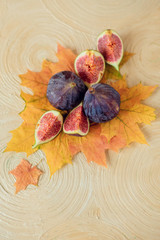 Fresh ripe figs with autumn leaves on a light background.