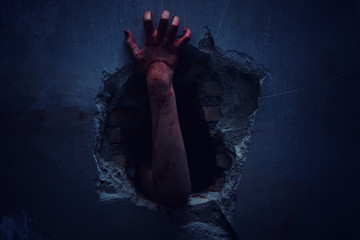 Horror Scene with bloody hand of evil is coming from a dark hole.