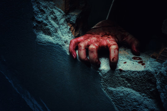 Horror Scene with bloody hand of evil is coming from a dark hole.