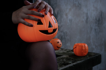 Young woman in witch Halloween costume hold a orange pumpkin