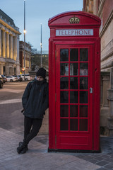 Boy waiting on a telephone booth in London, England, United Kingdom