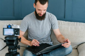 blogger lifestyle and working process. bearded hipster man sitting in front of camera holding laptop. live video streaming and social network business trends concept.