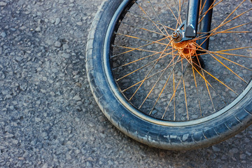 The abstract background with the children's bicycle wheel lying on the asphalt surface