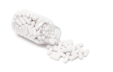 white medicine capsules spill out from bottle
