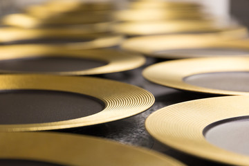 Gold rimmed round plates laid out on a restaurant table preparing to be used for dinner.