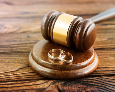hammer of a judge, a pair of gold wedding rings on a wooden background. family law, divorce and conflict.