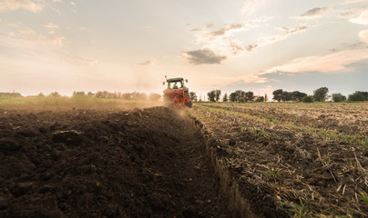 Fototapeta premium Farmer plowing stubble field