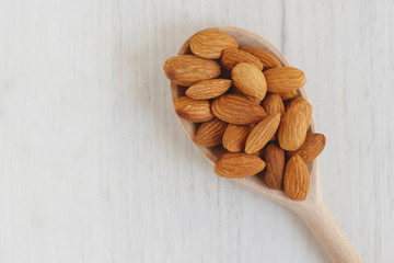almonds in a wooden spoon on a white background