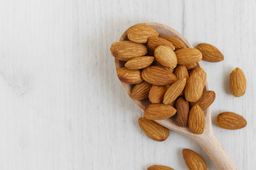 almonds in a wooden spoon on a white background