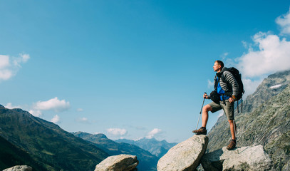 Hiker man with a backpack, on the mountain peak near pass Grand Ferret . Hiking around Mont Blanc, Switzerland part