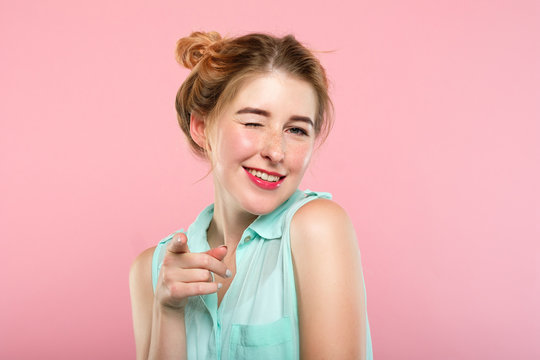 emotion and facial expression. flirty coquettish woman pleased with herself smiling and winking at viewer. young beautiful girl portrait on pink background.