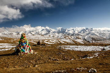 Pyramid of prayer flags in front of snow-covered mountains of the Himalayas at Lalung La pass, 5050m altitude on the Friendship Highway between Lhasa in Tibet and Kathmandu in Nepal