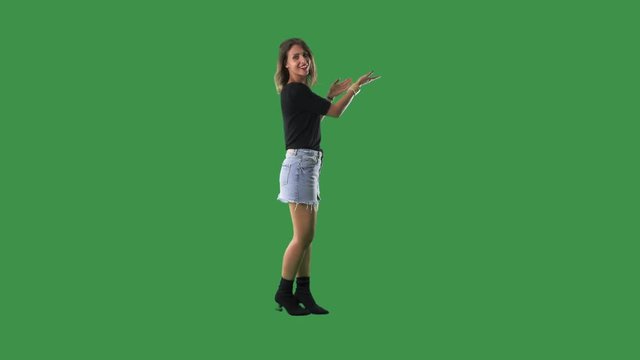 Young trendy casual woman advertising product over empty copy space. Full body isolated on green screen background. 