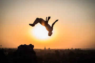 Foto op Plexiglas boy doing somersault on sunset background © Ishtvan