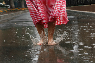 close-up of a girl's feet dancing in a puddle after a summer rain