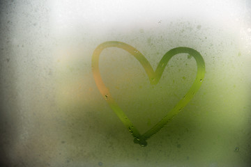 A heart painted on a misted window.Heart on misted glass. Heart on a window background.Heart symbol of love drawn on the glass.
