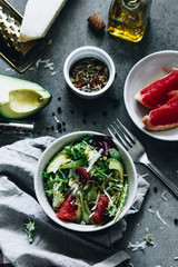Salad with rocket salad, avocado, grapefruit, parmigiano, olive oil on a grey background, top view