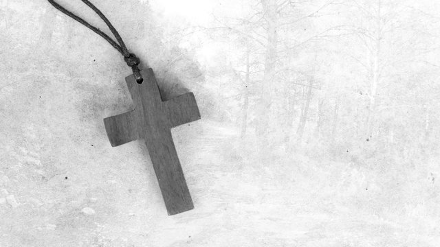 Holzkreuz liegt auf einer Steinplatte mit Waldmotiv