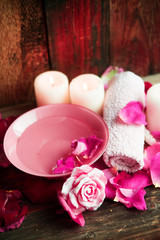Spa settings with roses. Fresh roses and rose petals in a bowl of water and various items used in spa treatments