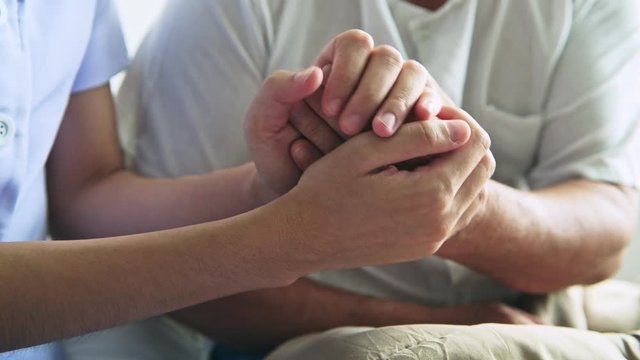 Comforting hand. Young nurse holding old man's hand. Senior care, care taker and senior retirement home service concept. Close up shot.