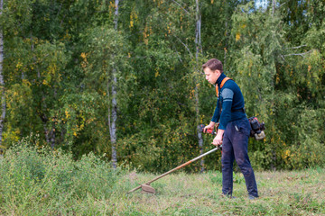 the young man mows the grass