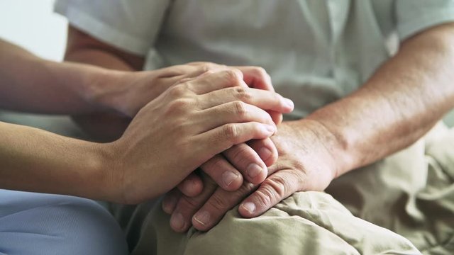Comfort hand. Nurse holding senior man hand.