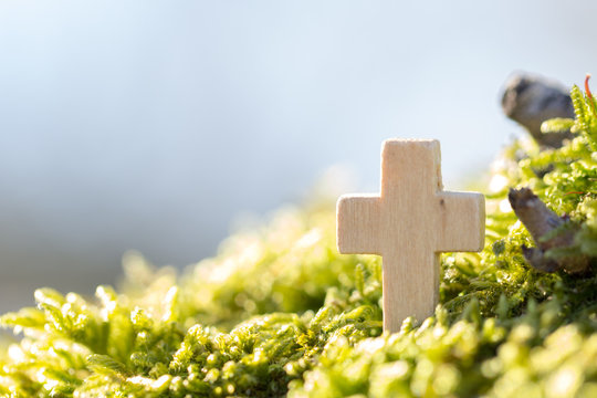 Holzkreuz im Gr&uuml;nen vor blauem Himmel
