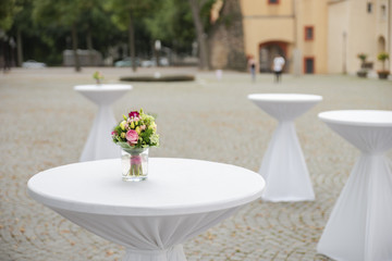kleiner Blumenstrauß auf einem mit weißen Stoff dekorierten Stehtisch