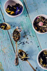 Flower tea: edible Pansy flowers, lemongrass, lavender, rose. Tea with flower petals on blue wooden background.