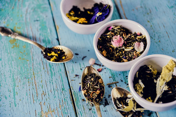 Flower tea, brewing: edible Pansy flowers, lemongrass, lavender, rose. Tea with flower petals on blue wooden background.