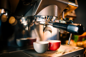 Close up details of brewing machinery pouring and preparing espresso in two cups. Cafe shop details