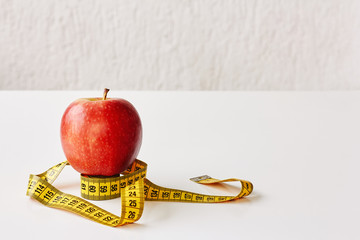 Measure tape and fresh fruit apple on white background. Loss weight, slim body, healthy diet concept