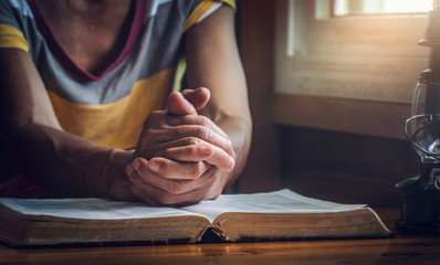 focus on a hands of old woman while praying on Bible, christian concept - obrazy, fototapety, plakaty