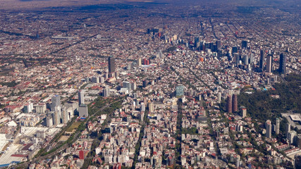 Mexico City, Mexico - Jan 2016: A Volaris passenger plane flies over the skyscrapers and parks of the central business district of Mexico City